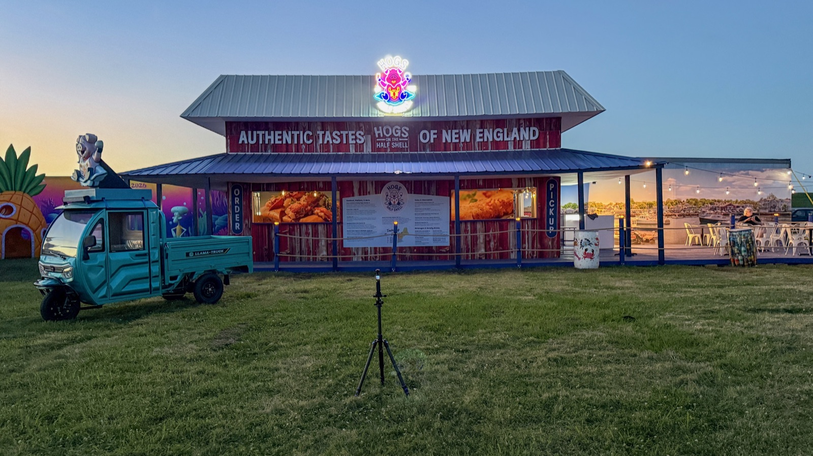The 2026 Hogs on the Half Shell booth glowing at dusk