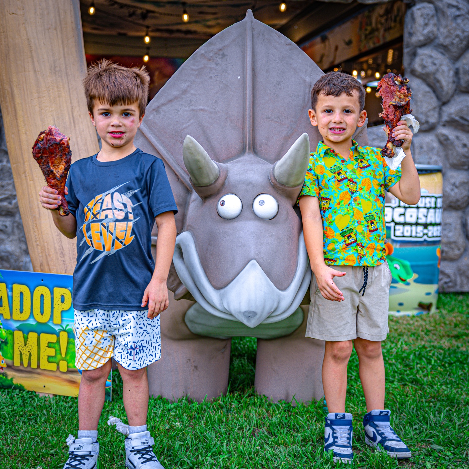 Two kids holding giant dino-style ribs at the Hogosaurus booth