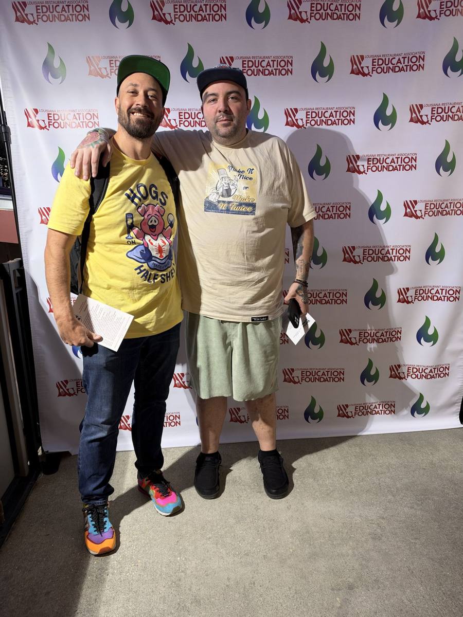Two House of Hogs teammates on the LRA Education Foundation step-and-repeat, one in a Hogs on the Half Shell shirt