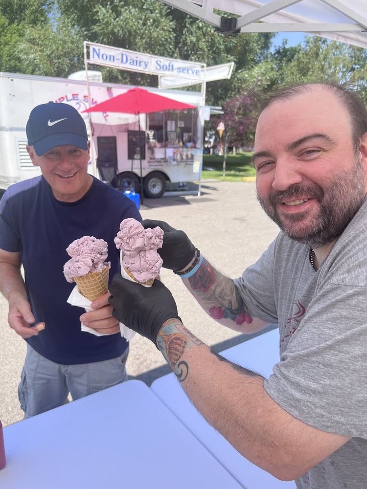 Two friends toasting with huckleberry soft-serve cones from a neighboring trailer